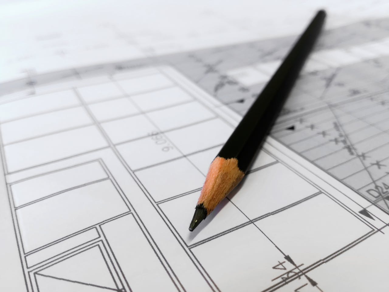 Despre Detailed image of a black pencil resting on architectural blueprints, ideal for design and planning themes.